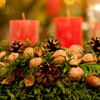 Ein voller Adventskranz mit Nüssen, Zapfen und roten Kerzen.